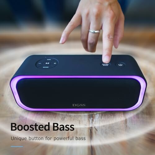 Hand pressing button on wireless speaker with purple LED light.